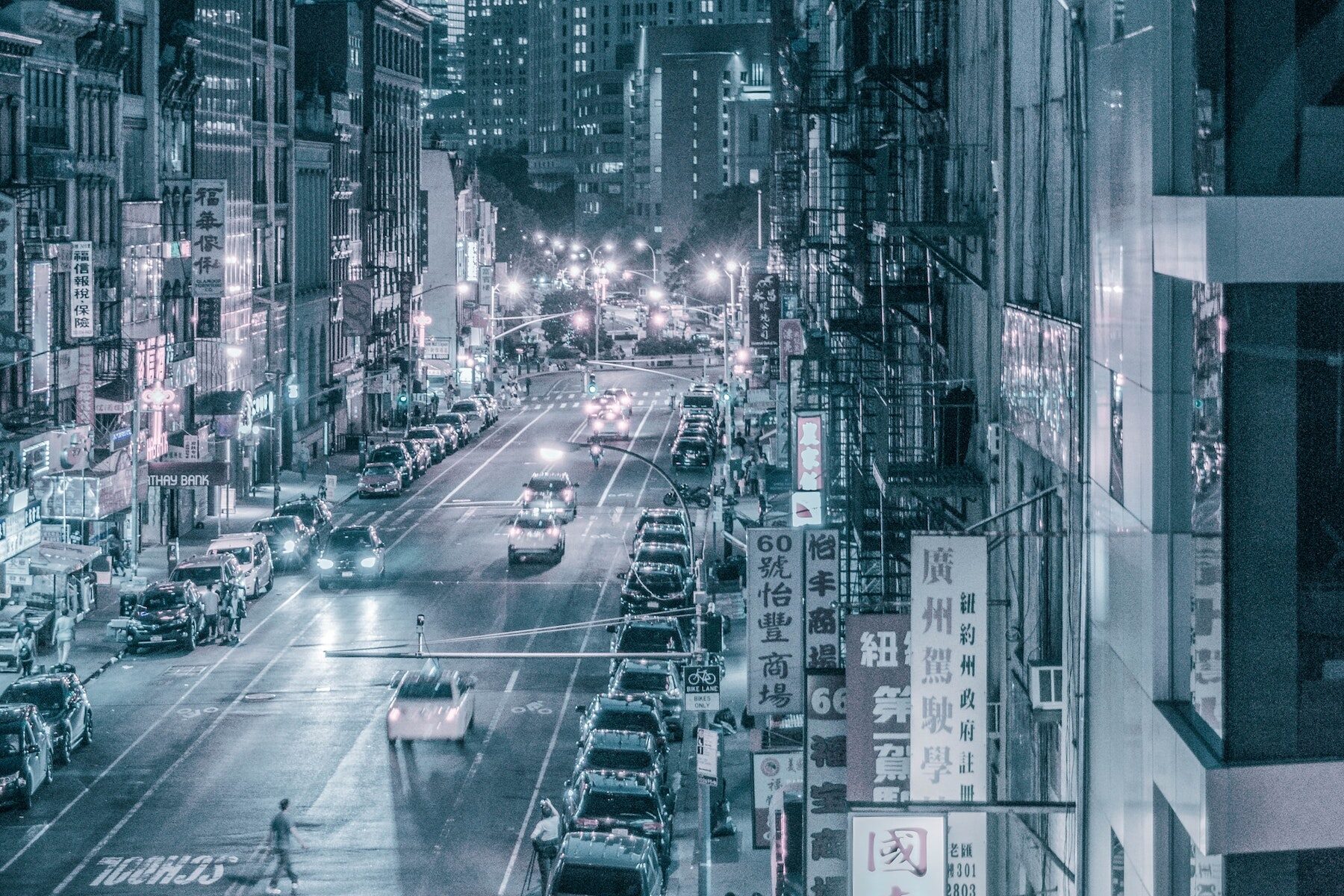 A photo of a New York City Chinatown street. There are cars on the street and signs along the buildings. Photo by Mauricio Chavez on Unsplash.